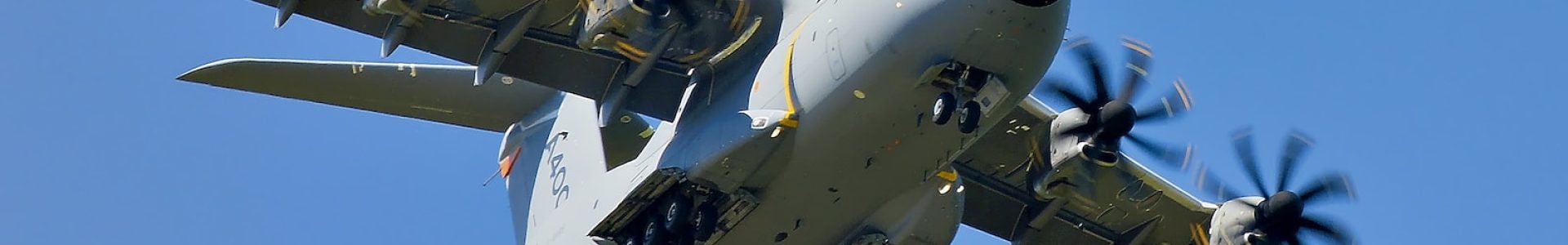 grey military cargo plane on flight under clear blue sky